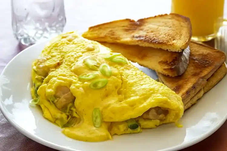 Creole omelette with toast on a white plate, garnished with green onions.